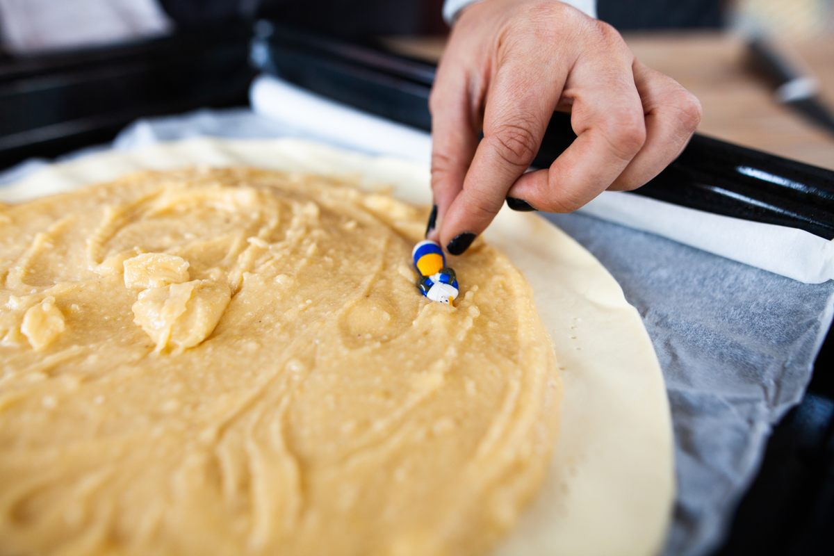 Un panadero introduce una fève en una galette des rois antes de hornearla.