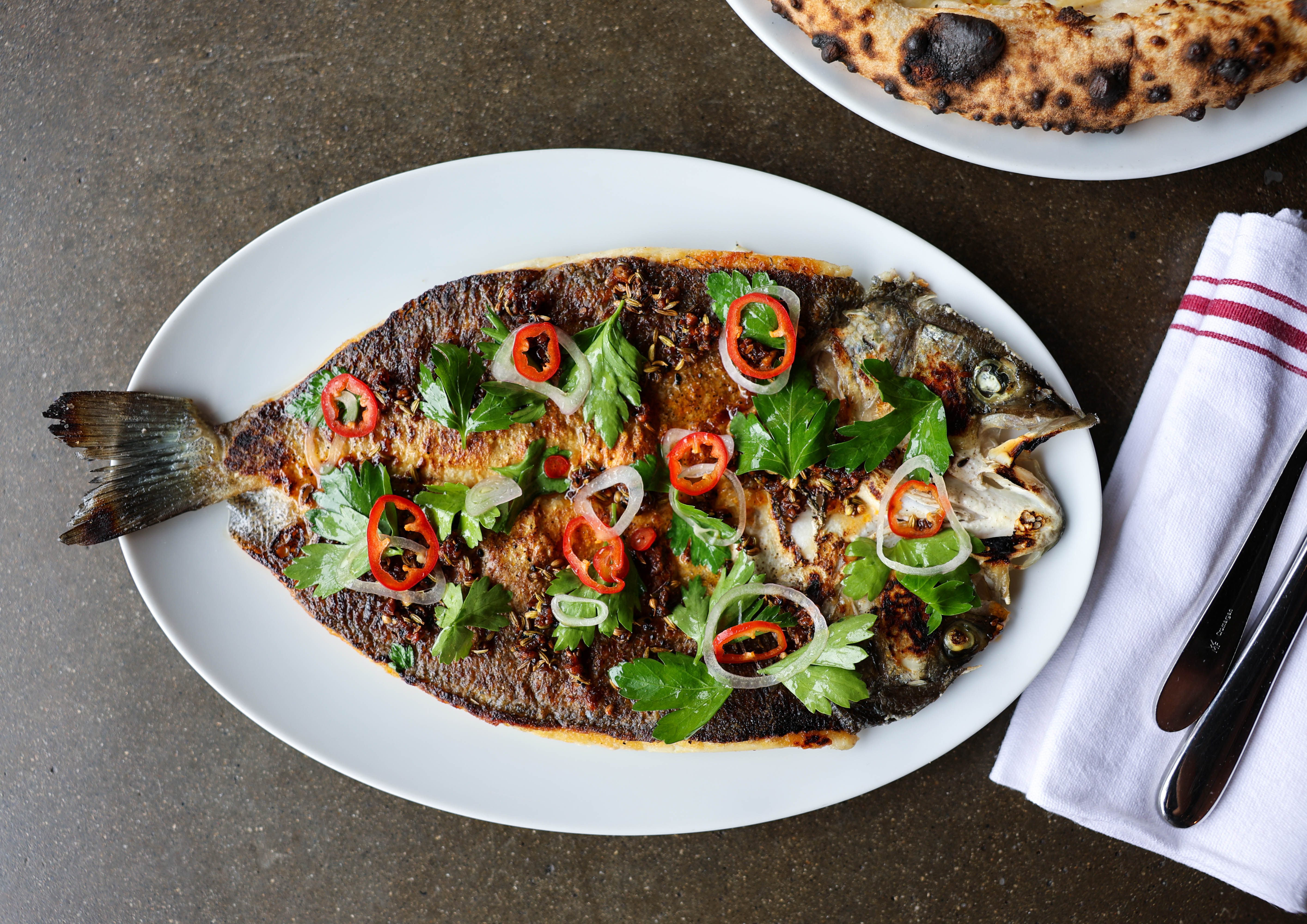 Los platos de Bestia están diseñados para compartir, como este branzino entero asado cubierto con chiles fresno, albahaca y pesto. 