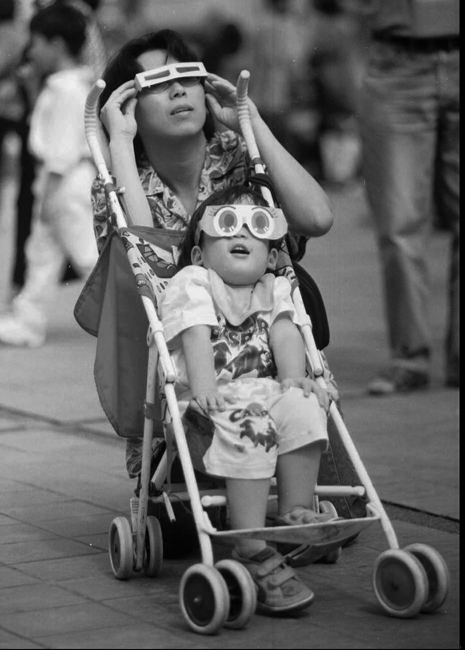 Una madre y su hijo observan el eclipse solar en Bangkok, Tailandia, 1995. 