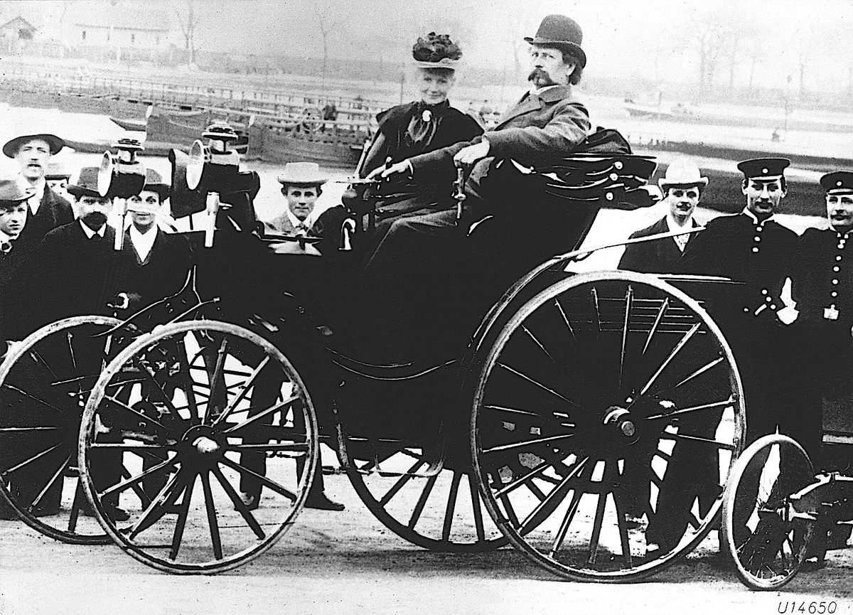 Bertha Benz (centro) sentada junto a su marido, Karl Benz, en un Benz Patent-Motorwagen Viktoria de 1894.