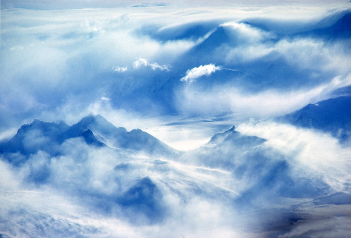 En el mundo sin vida de la Antártida, el viento es una fuerza animadora.  Es portador de nubes y libertador de nieve.  Puede ser una fuerza temible que avanza a través de las montañas.  En esta imagen, el viento arroja nubes sobre Heinous Peak (arriba a la derecha, en el centro) y el Monte Pulitzer (abajo a la izquierda).