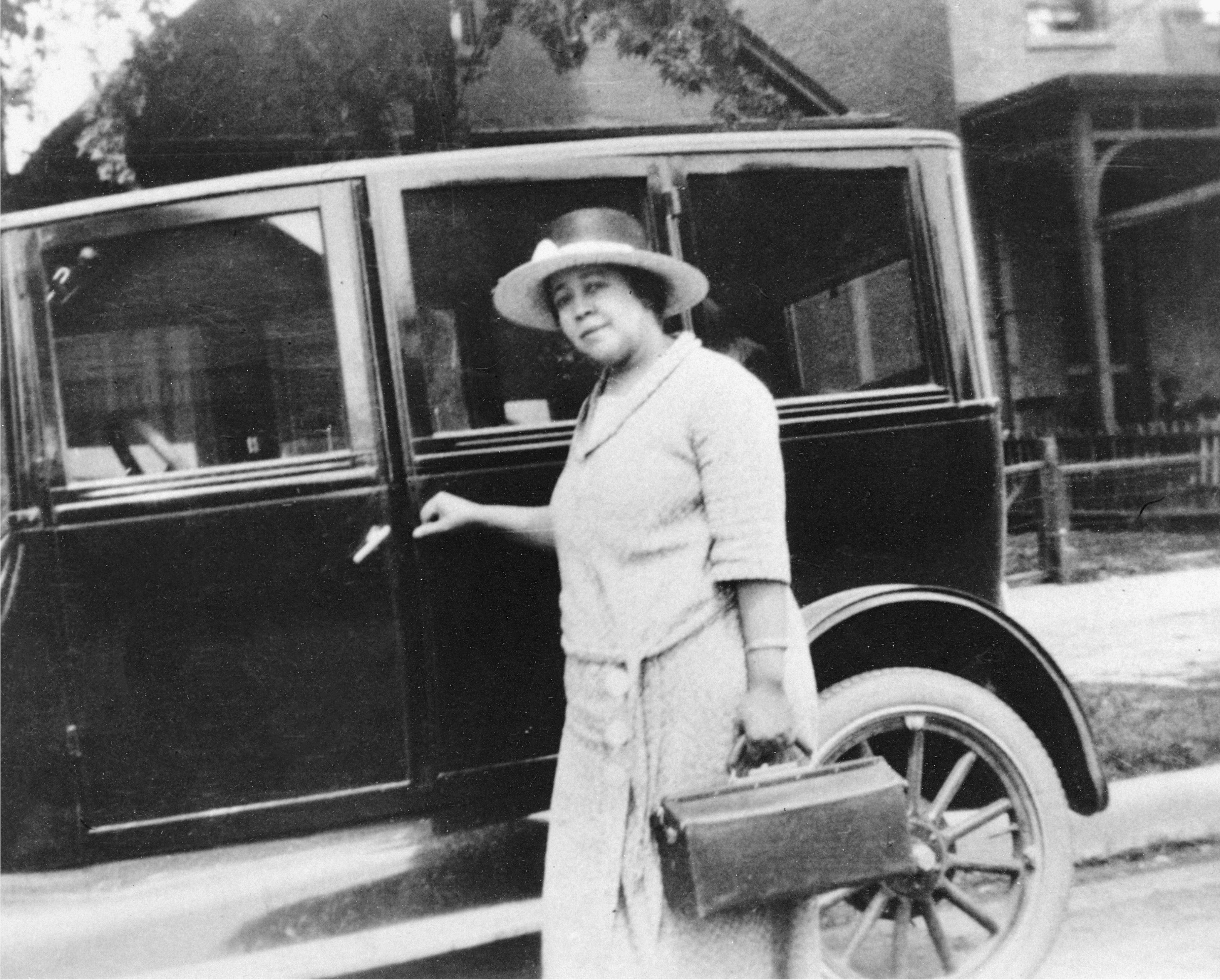 La Dra. Justina Ford se sube a un automóvil con su maletín de médico, probablemente de camino a hacer una visita a domicilio, alrededor de 1920.