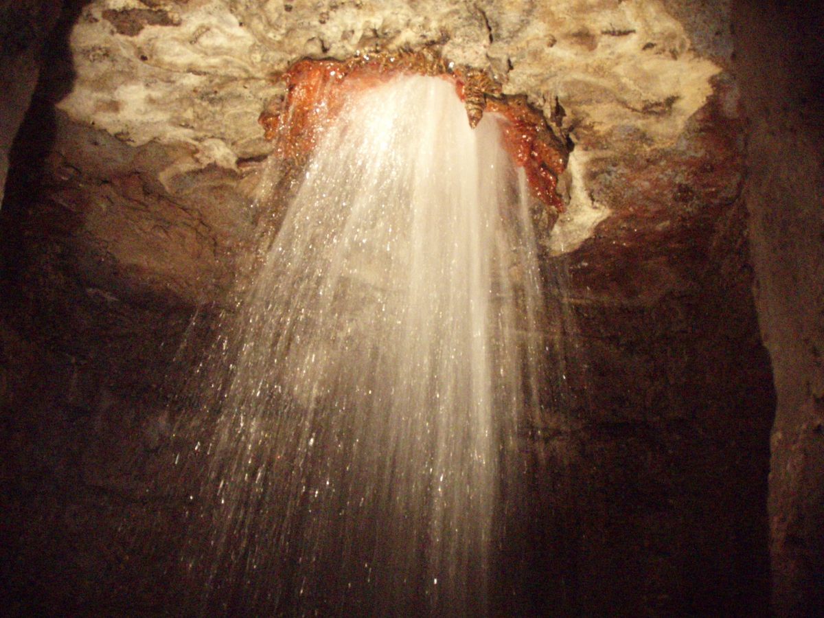 Un antiguo pozo artesiano rocía agua subterránea dentro de la cueva; el agua que cae desde arriba puede levantar material rico en bacterias conocido cortésmente como "aerosoles coliformes."