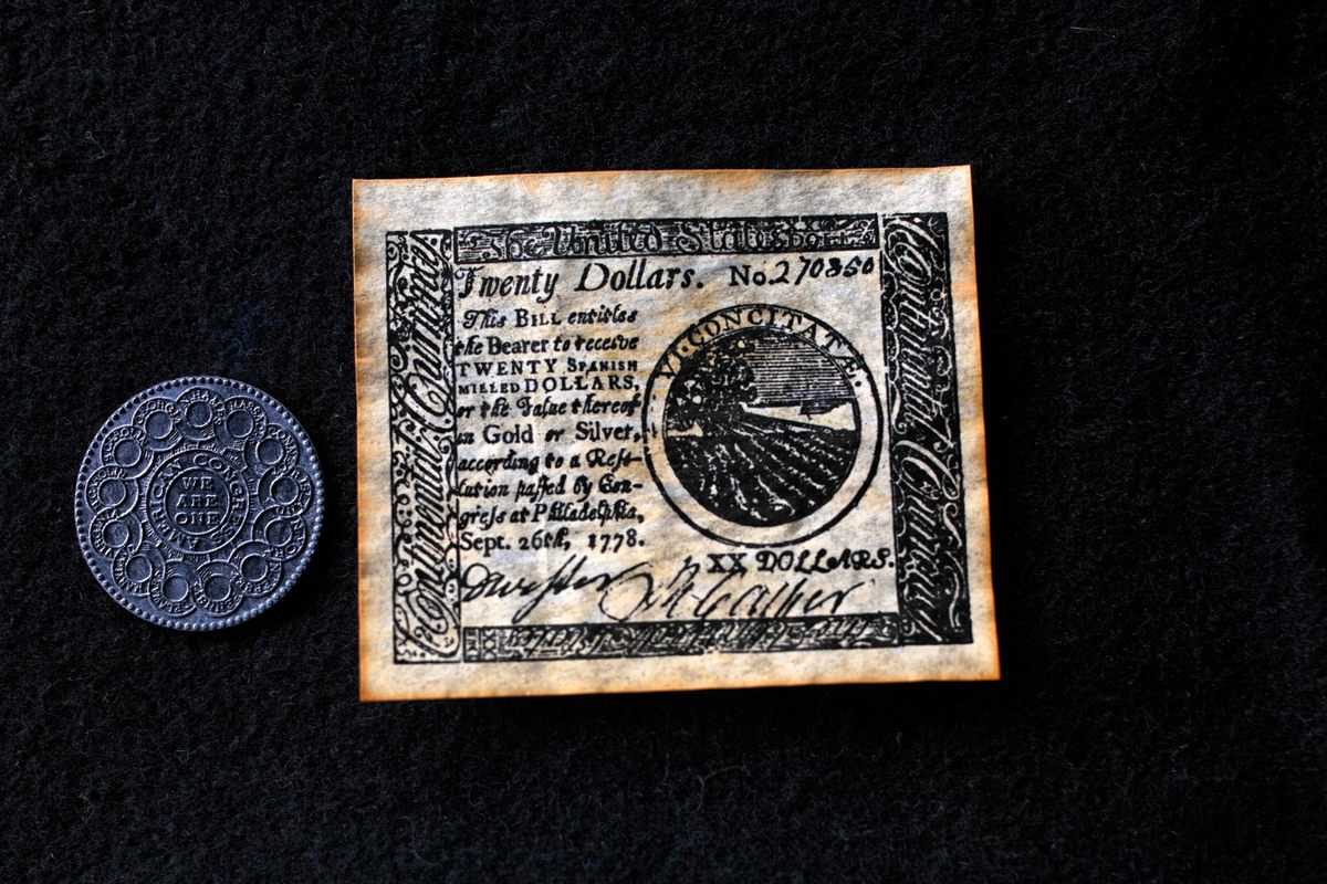 Una antigua moneda americana redonda junto a un papel moneda de 20 dólares, fechada en 1778.