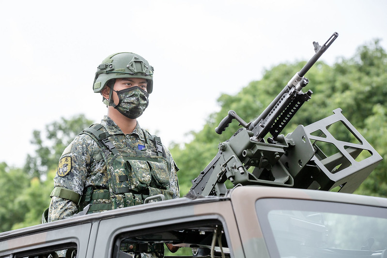 Un soldado taiwanés de pie detrás de un vehículo.