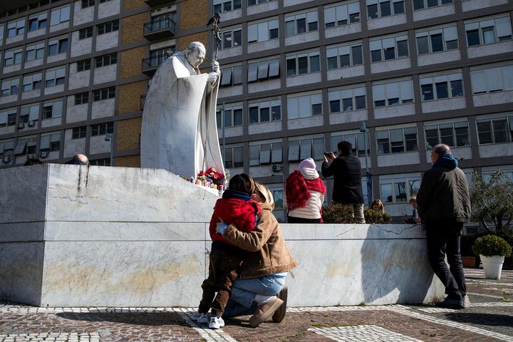 Varios fieles llevaron flores a la estatua del Papa Juan Pablo II emplazada frente al hospital Gemelli, en Roma, donde está internado Francisco. Foto: EFE  