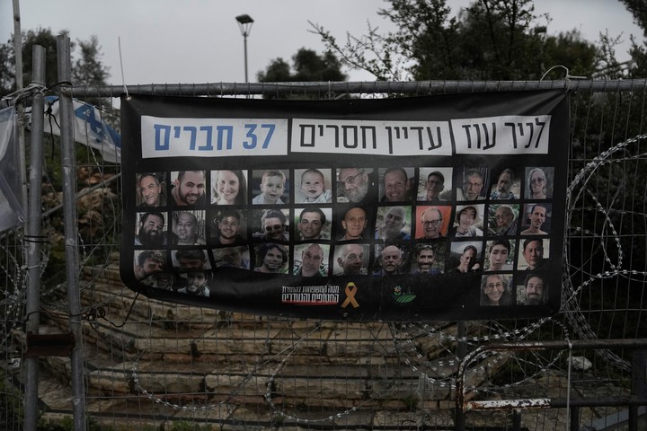 Un cartel muestra retratos de la familia Bibas, fila superior desde la segunda a la izquierda: Yarden, Shiri y sus hijos Ariel y Kfir, secuestrados en Gaza el 7 de octubre de 2023, en Jerusalén, el viernes 21 de febrero de 2025. Las letras de la parte superior dicen: "37 miembros del kibutz Nir Oz siguen desaparecidos". (AP Photo/Mahmoud Illean)