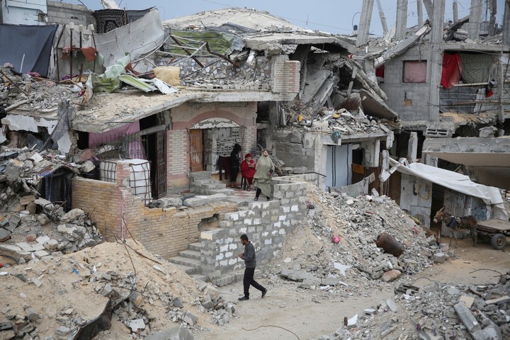 Una familia palestina, frente a un edificio destruido por la ofensiva de Israel, en Jan Younis, sur de la Franja de Gaza. Foto: REUTERS 