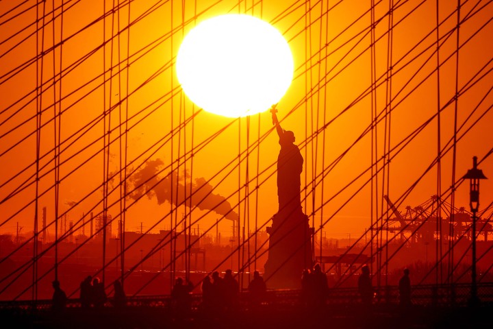 El Sol se pone sobre la Estatua de la Libertd y el puente de Brooklyn. Foto: AFP