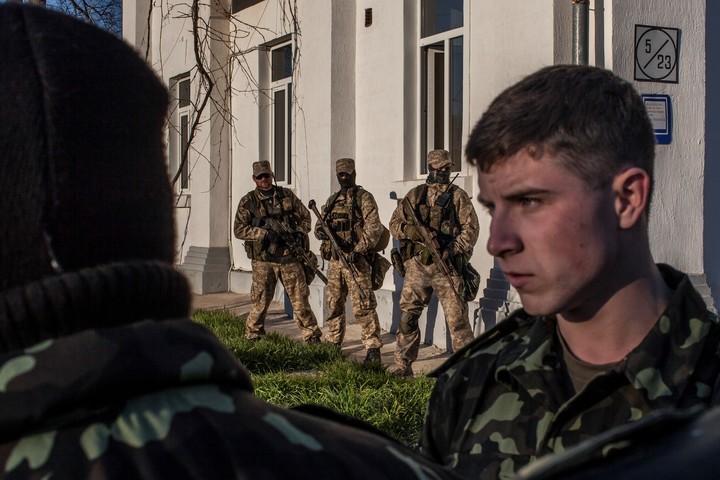 Soldados ucranianos miran hacia las tropas rusas que se acercan en Belbek, Crimea, 22 de marzo de 2014. Un nuevo plan de paz de Estados Unidos ofrecido a Rusia y Ucrania propone el reconocimiento estadounidense de la península, de la que Moscú se apoderó en 2014. (Mauricio Lima/The New York Times)