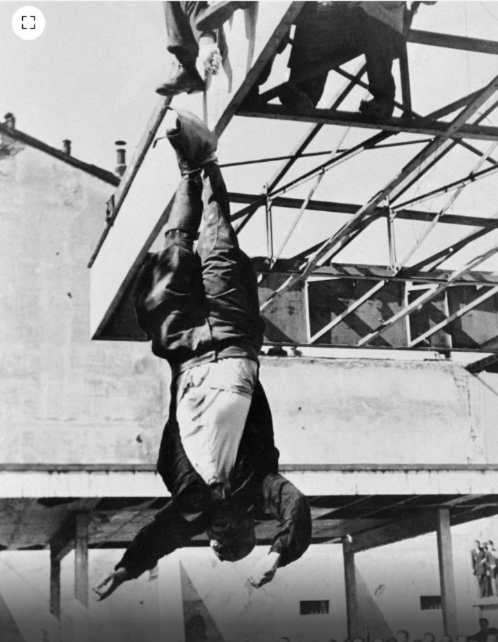 Los partisanos comunistas izan el cuerpo sin vida de Benito Mussolini en la estación de servicio de Milán (AP)