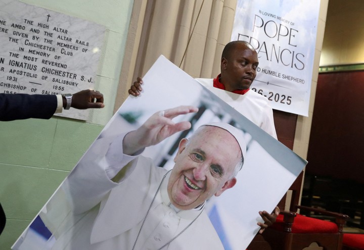 Un acomodador sostiene una imagen que muestra al papa Francisco en una misa en Harare, Zimbabue. Foto Reuters