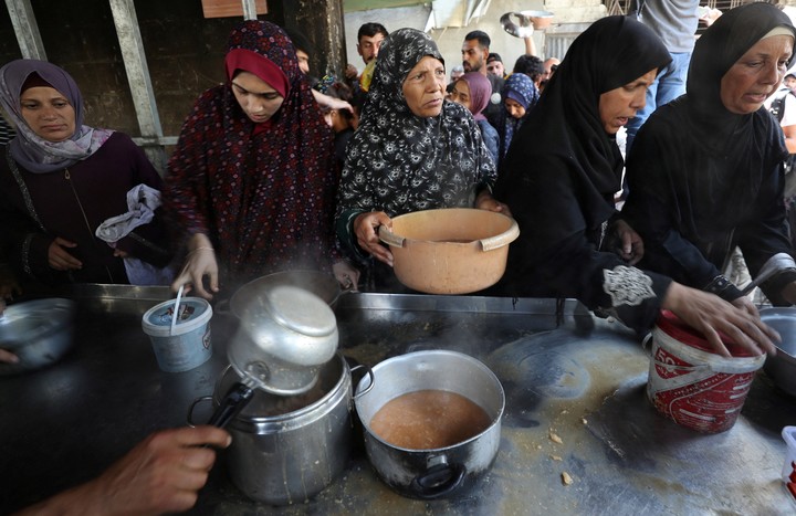Palestinos hacen fila para recibir un plato de comida. Foto: Reuters