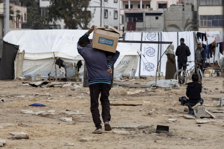 Un joven lleva una caja de ayuda alimentaria a su tienda de campaña en el centro de la ciudad de Gaza, el 7 de febrero de 2025. La prohibición por parte de Israel de los envíos de alimentos y medicamentos a Gaza ha provocado llamamientos de la comunidad internacional, incluidos sus aliados, para que se ponga fin al bloqueo. (Saher Alghorra/The New York Times)