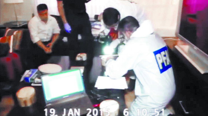 Técnicos de la División Operaciones de Técnicas Especiales de la Policía Federal toman huellas de la computadora y el celular de Nisman el 18 de enero. /Captura de video