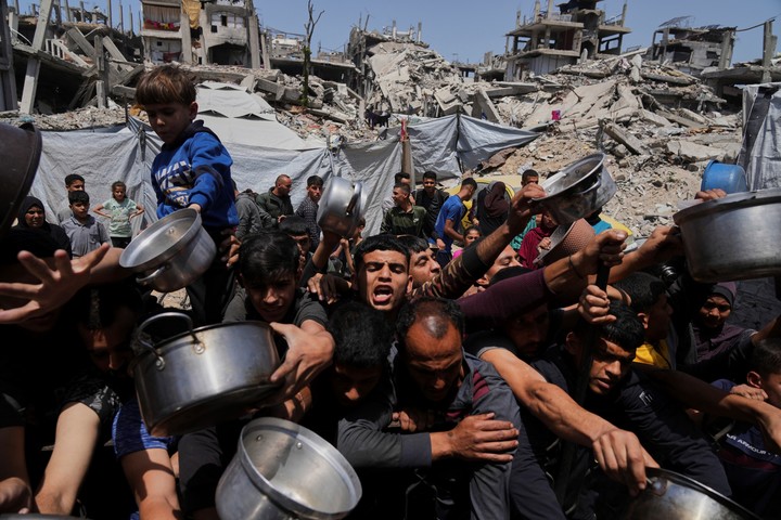 Palestinos luchan por conseguir alimentos donados en un comedor comunitario de Beit Lahia, en el norte de la Franja de Gaza, el 3 de mayo de 2025. (AP Photo/Jehad Alshrafi)