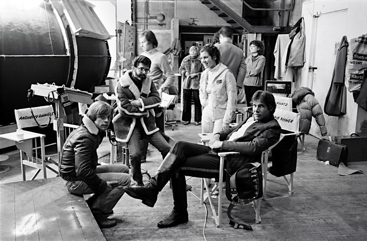 Un joven George Lucas, sentado con un gamulán, y las tres estrellas de las primeras entregas de la saga: Luke Skywalker, la princesa Leia y Han Solo, en un alto de la filmación. 
Foto: Taschen.