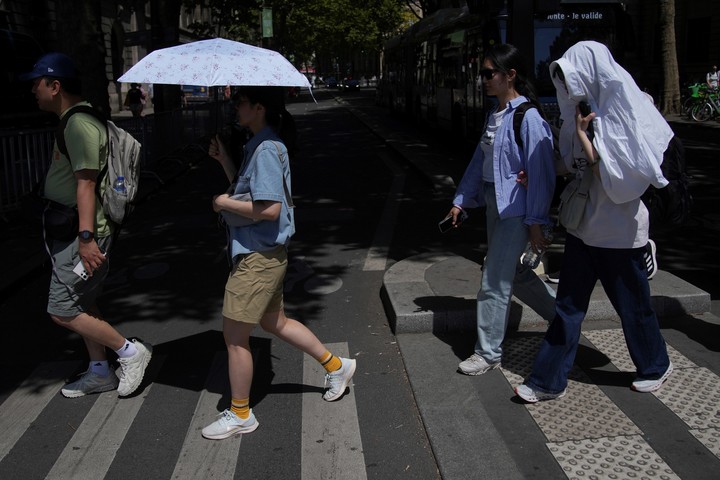 Toristas se cubren del sol, en París. Foto: AP