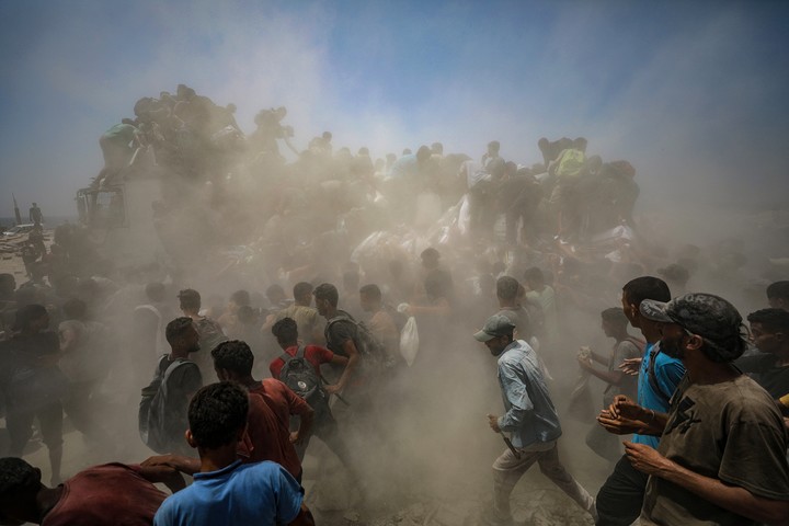 Palestinos desplazados internos intentan recoger sacos de harina de un camión de ayuda humanitaria. Foto EFE