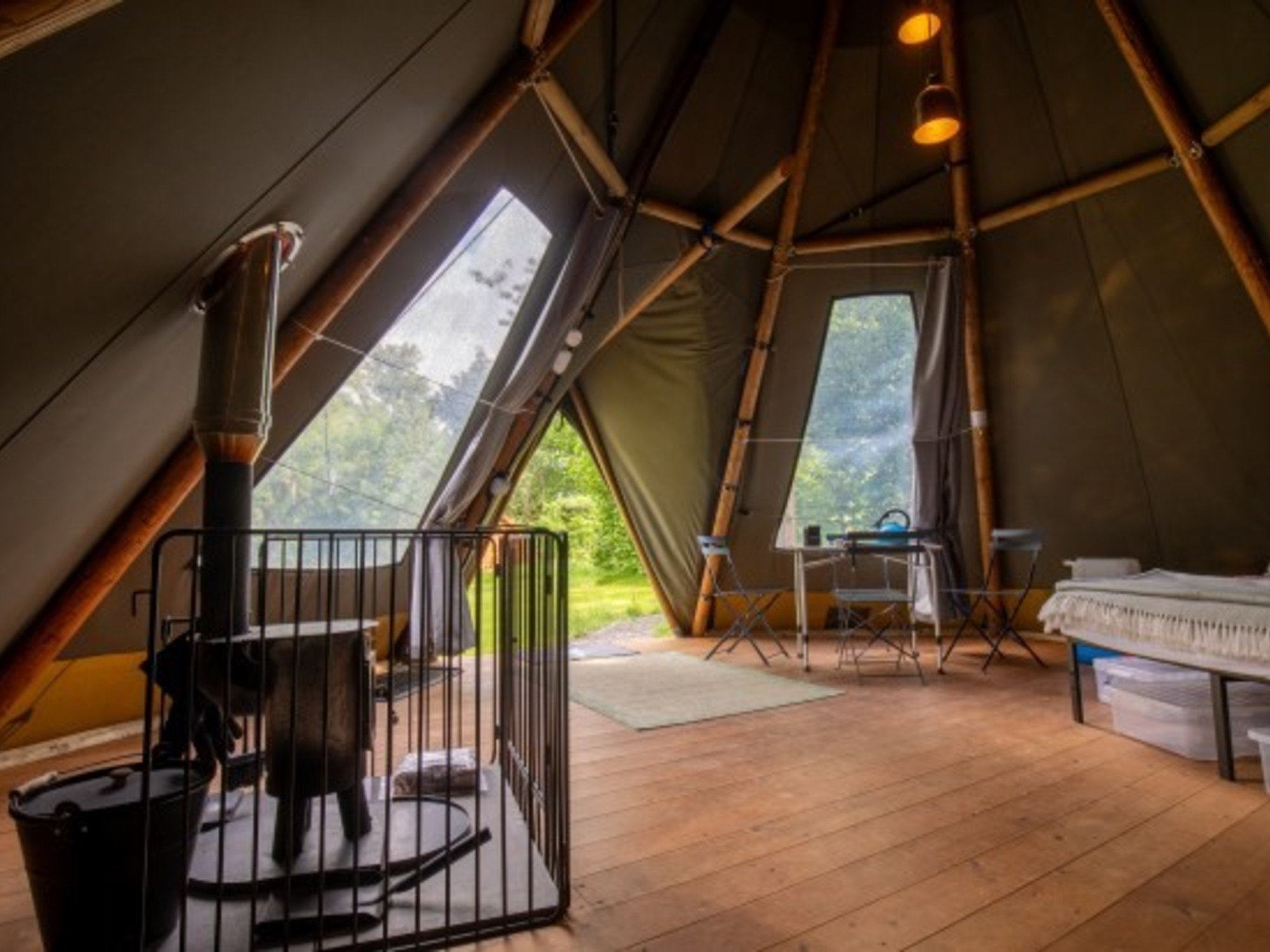 Detalles increíbles de una carpa con cama, mesa y estufa sobre piso de madera en medio de la naturaleza./ Glampings National Trust Wasdale Campsite, Seascale, Cumbria./ Imagen de The Times.
