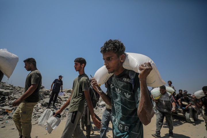 Palestinos desplazados internos cargan sacos de harina cerca de un punto de distribución de alimentos en Zikim, al norte de la Franja de Gaza, Foto EFE