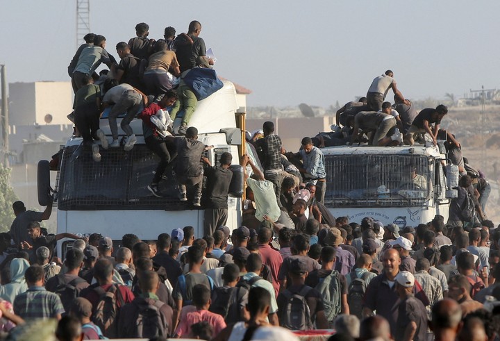Decenas de palestinos suben a camiones que llevan alimentos entregados por organizaciones humanitarias. Foto: REUTERS  