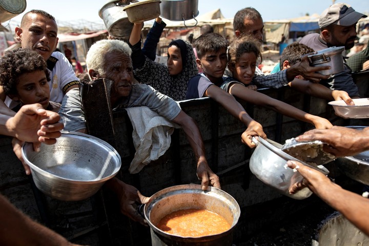Desplazados palestinos piden un plato de comida en Gaza. Foto: EFE 